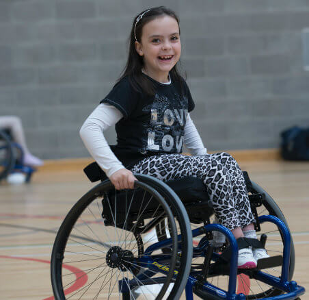 A smiling child using a wheelchair