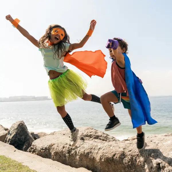 Foster care boy and girl wearing super hero costumes at the beach.