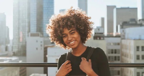 A Texas foster care teen on a roof top of a building happily posing for a photo.