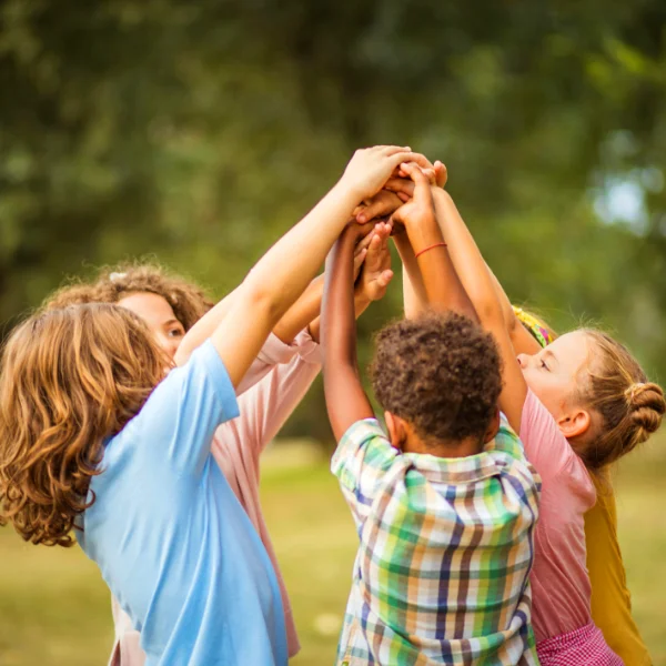 Foster care kids interlocking hands while they play at the park on a sunny day.
